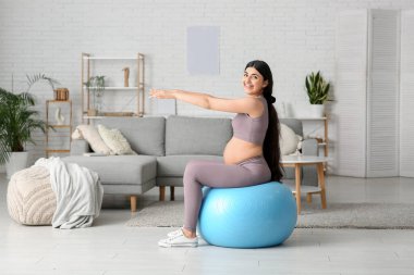 Güzel hamile kadın evde spor yapıyor.