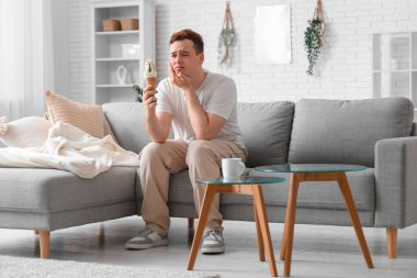 Dondurmalı genç adam oturma odasında diş ağrısı çekiyor.