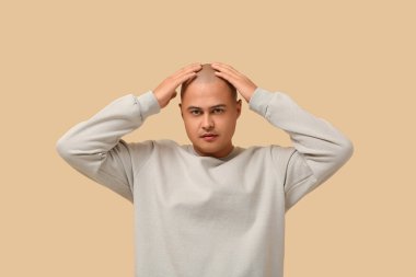 Bej arka plandaki kel genç adam.