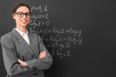 Sınıfta yazı tahtasının yanında genç bayan matematik öğretmeni.