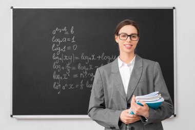 Sınıfta yazı tahtasının yanında genç bayan matematik öğretmeni.