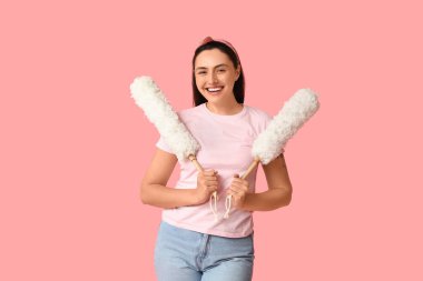 Pembe arka planda pp-tozster 'ları olan güzel, genç bir kadın.