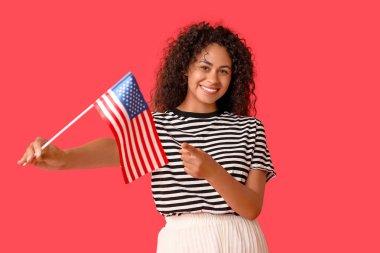 Kırmızı arka planda Amerikan bayrağı olan genç Afro-Amerikalı kadın.