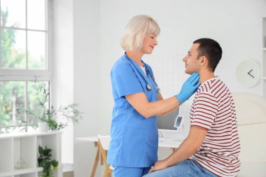 Kadın endokrinolojist klinikteki adamın tiroit bezini inceliyor.