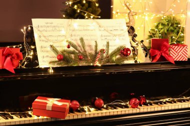 Kırmızı Noel topları ve piyanonun üzerindeki hediye kutusu.