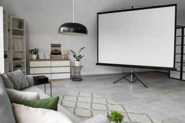 Projektör ekranı, raf ünitesi ve klozeti olan ışık oturma odasının içi