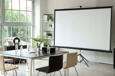 Projektör ekranı ve toplantı tablosu olan ofis içi