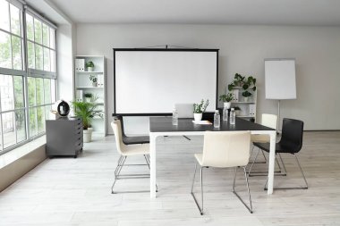 Projektör ekranı ve toplantı tablosu olan ofis içi