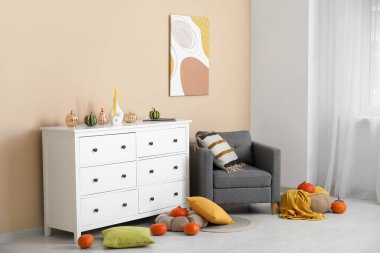 Siyah koltuklu, çekmeceli, balkabaklı ve minderli bir sonbahar salonu.