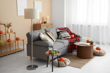 Oturma odasının sonbaharında rahat bir kanepe, lamba, balkabağı ve sehpası vardı.