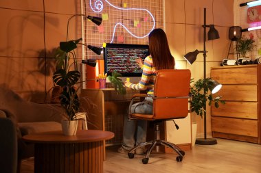 Gece ofiste bilgisayarla çalışan kadın programcı, arka plan görünümü