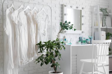 Masası, elbise askısı ve raf ünitesi olan makyaj odasının içinde.