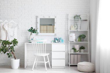 Masası, elbise askısı ve raf ünitesi olan makyaj odasının içinde.