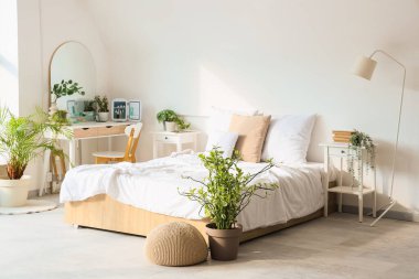 Makyaj masası ve bitkilerle aydınlık yatak odasının içinde.