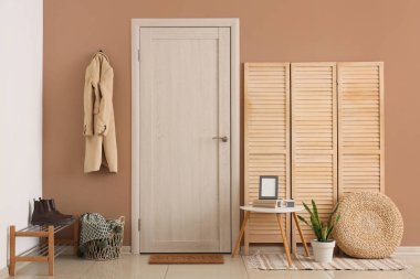 Beyaz perdeli, kapısı ve ceketi bej duvarda asılı şık bir koridor.