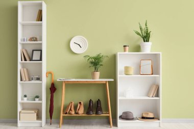 Duvar kenarında ayakkabı standı, saat ve raf üniteleri olan şık bir koridor.