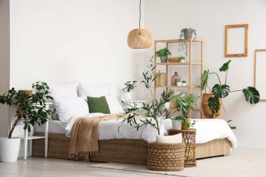 Büyük yatağı, raf ünitesi ve birçok farklı bitkisi olan rahat bir yatak odası.