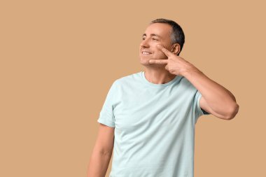 Mutlu olgun bir adam bej arka planda yüz geliştirme egzersizi yapıyor.
