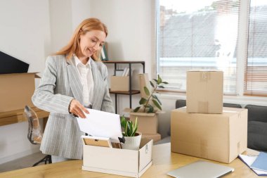 Olgun bir iş kadını taşınma gününde evrakları kutuya koyar.