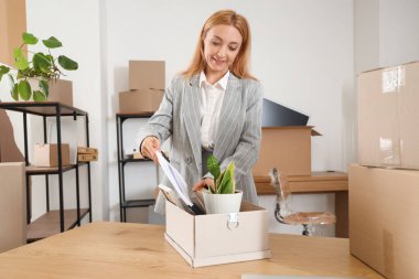 Olgun bir iş kadını taşınma gününde evrakları kutuya koyar.