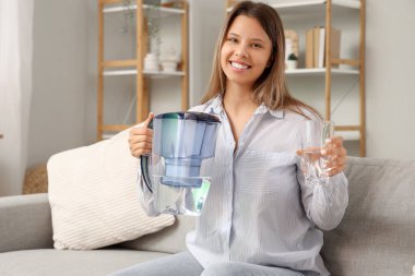 Su filtresi sürahisi ve camla evde genç bir kadın.
