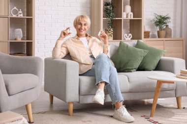 Evde göz damlası olan olgun bir kadın.