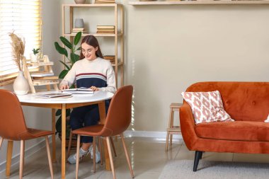 Oturma odasında kitap okuyan genç bir kadın.