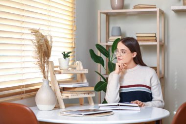 Oturma odasında kitap okuyan genç bir kadın.