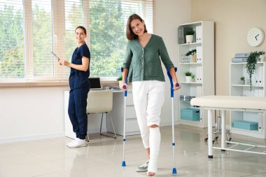 Bacağı kırık ve koltuk değnekleriyle kliniğe gelen genç bir kadın.