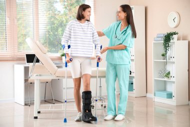 Bacağı kırık genç bir kadın ve klinikte bir doktor.