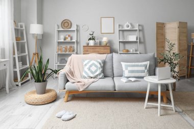 Oturma odasının içinde şık bir kanepe, raflar ve sehpanın üstünde dizüstü bilgisayar var.