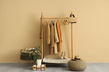 Palto askılı, çantalı ve puflu bir oda.