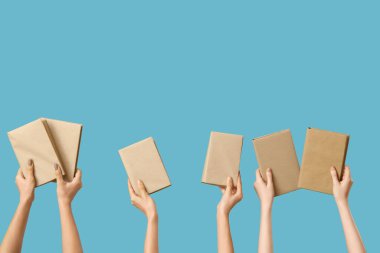 Mavi arka planda bir sürü kitap tutan eller