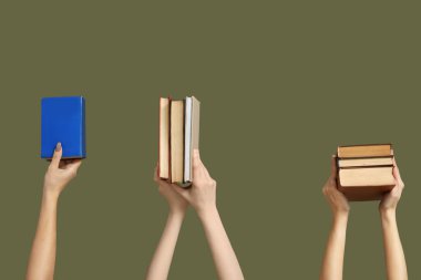 Renk arkaplanı üzerine birçok kitap tutan eller