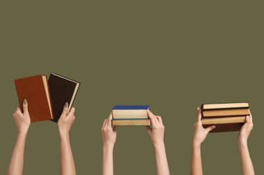 Renk arkaplanı üzerine birçok kitap tutan eller