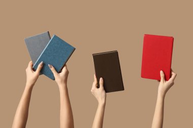 Bej arkaplan üzerine birçok kitap tutan eller