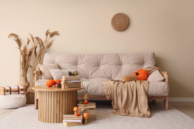 Konforlu kanepe, sehpa ve sonbahar dekoru oturma odasındaydı.