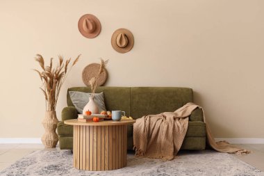 Ekoseli kanepe, yastık, sehpa ve sonbahar dekoru oturma odasının içinde.