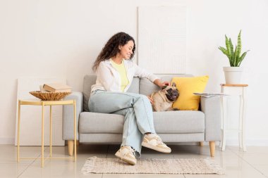 Güzel, genç, Afro-Amerikan bir kadın ve tatlı bir Fransız bulldog 'u oturma odasında kanepede oturuyor.