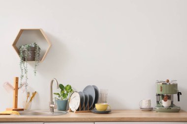 Mutfakta lavabonun yanında temiz tabaklar ve modern kahve makinesi olan tutucu.