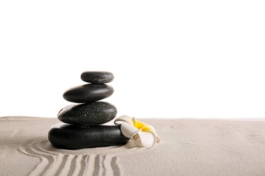 Stack of black stones and tropical flower on sand with lines against white background. Zen concept clipart