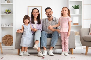 Evdeki kanepede oturan güzel, mutlu bir aile.