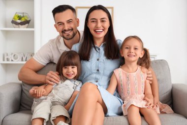 Evdeki kanepede oturan güzel, mutlu bir aile.