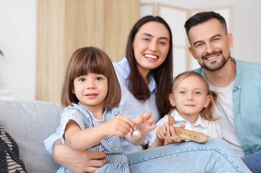 Mutlu bir aile evdeki kanepede tahta uçakla oynuyor.