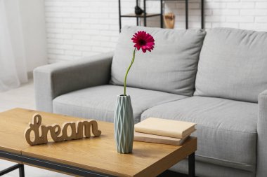 Güzel Gerbera çiçeği, ahşap kelime DREAM ve oturma odasındaki masada kitaplar.