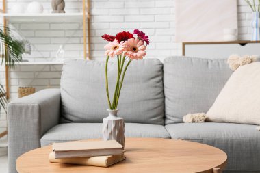 Vazodaki güzel Gerbera çiçekleri ve oturma odasındaki masada kitaplar.