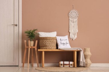 Yastıklı ahşap bank, sepet ve ekose kahverengi duvarlı oda