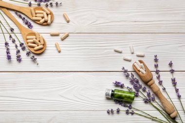 Beyaz ahşap arka planda farklı haplar ve lavanta çiçekleri içeren kompozisyon