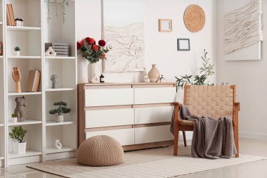 Oturma odasının iç tarafında yıldız çiçekleri olan raf ünitesi, koltuk ve çekmeceler.