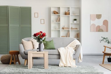 Oturma odasının iç tarafındaki rahat kanepenin yanındaki kahve masasında Dahlia çiçekleri.